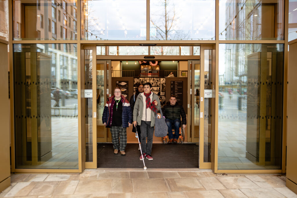 A venue entrance with a wide doorway, automatic doors with manifestations and level access between the outdoors and lobby.