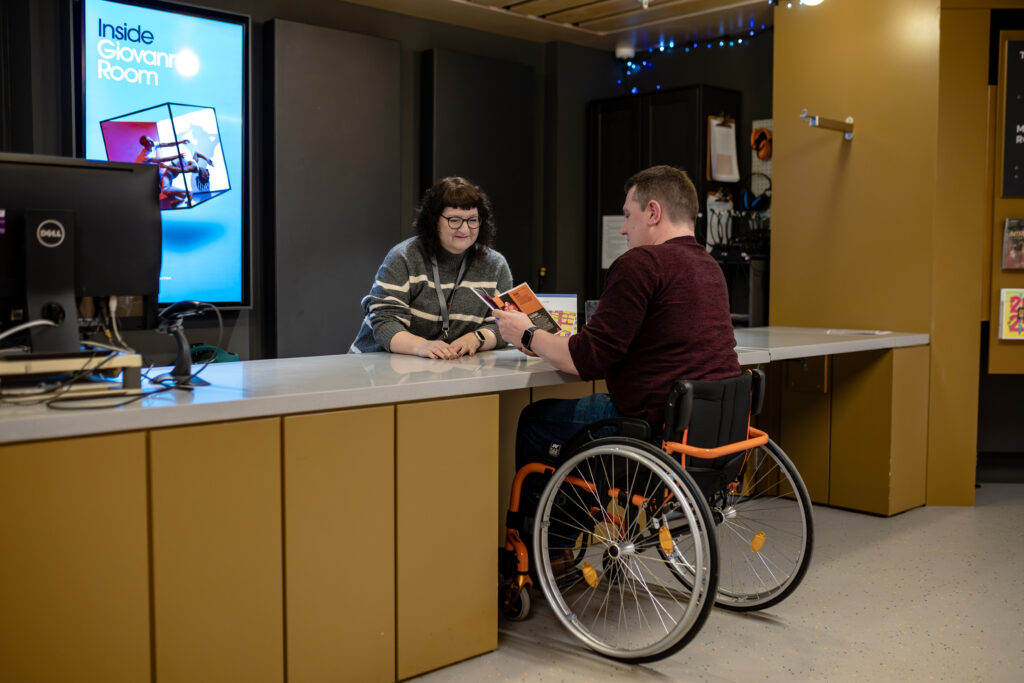 A box office counter with clear access and a wide lowered counter with knee recess. Evenly lit with non-reflective surfaces.