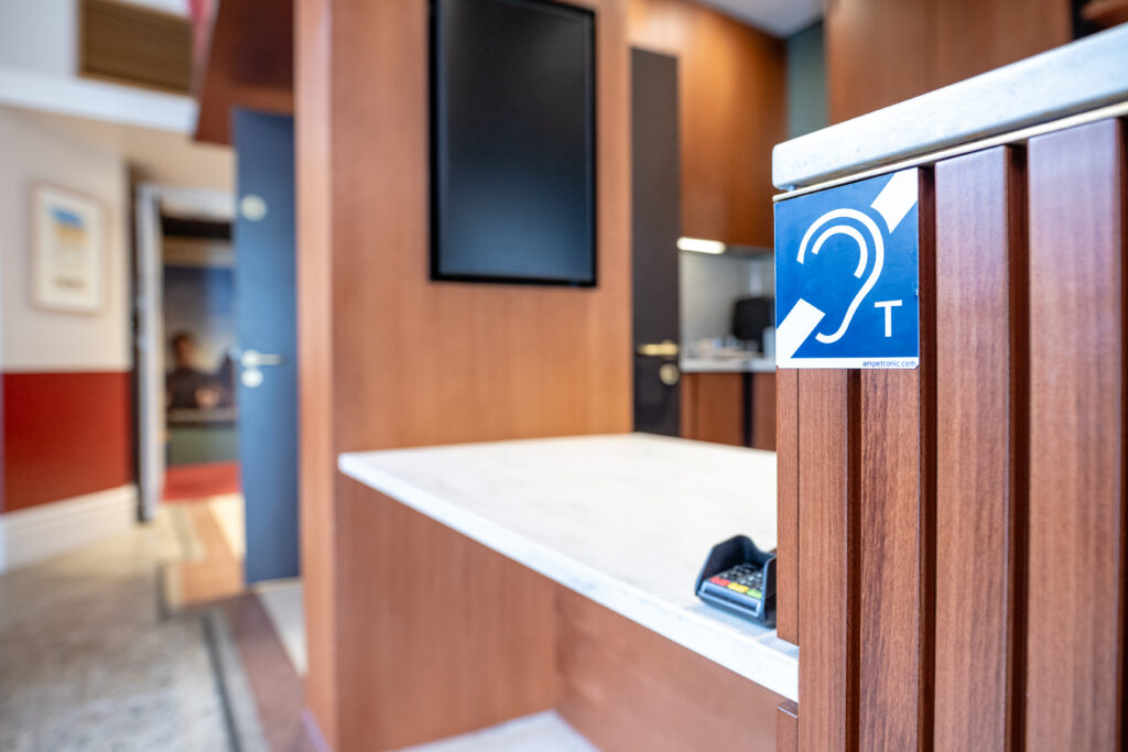 A lowered accessible café counter with a blue and white sign showing that an induction loop is available to use here.