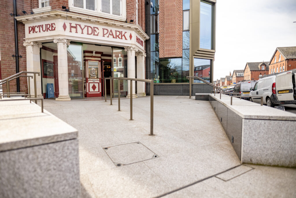 Gently sloped approach to a cinema entrance with handrails and seating.