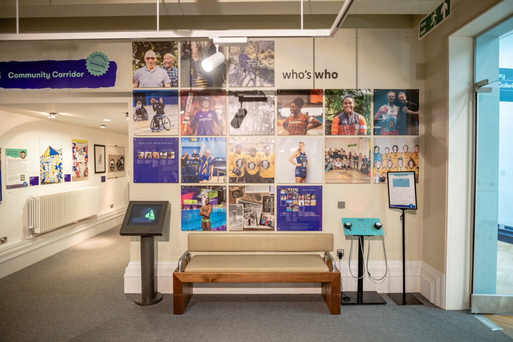 A bench with a padded seat and backrest and arm supports provides a place to rest in a museum gallery.