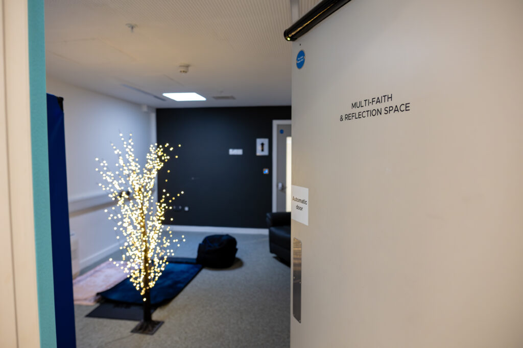 A door labelled ‘multi-faith and reflection space’ opens into a room with twinkling tree-shaped lights and soft seating.