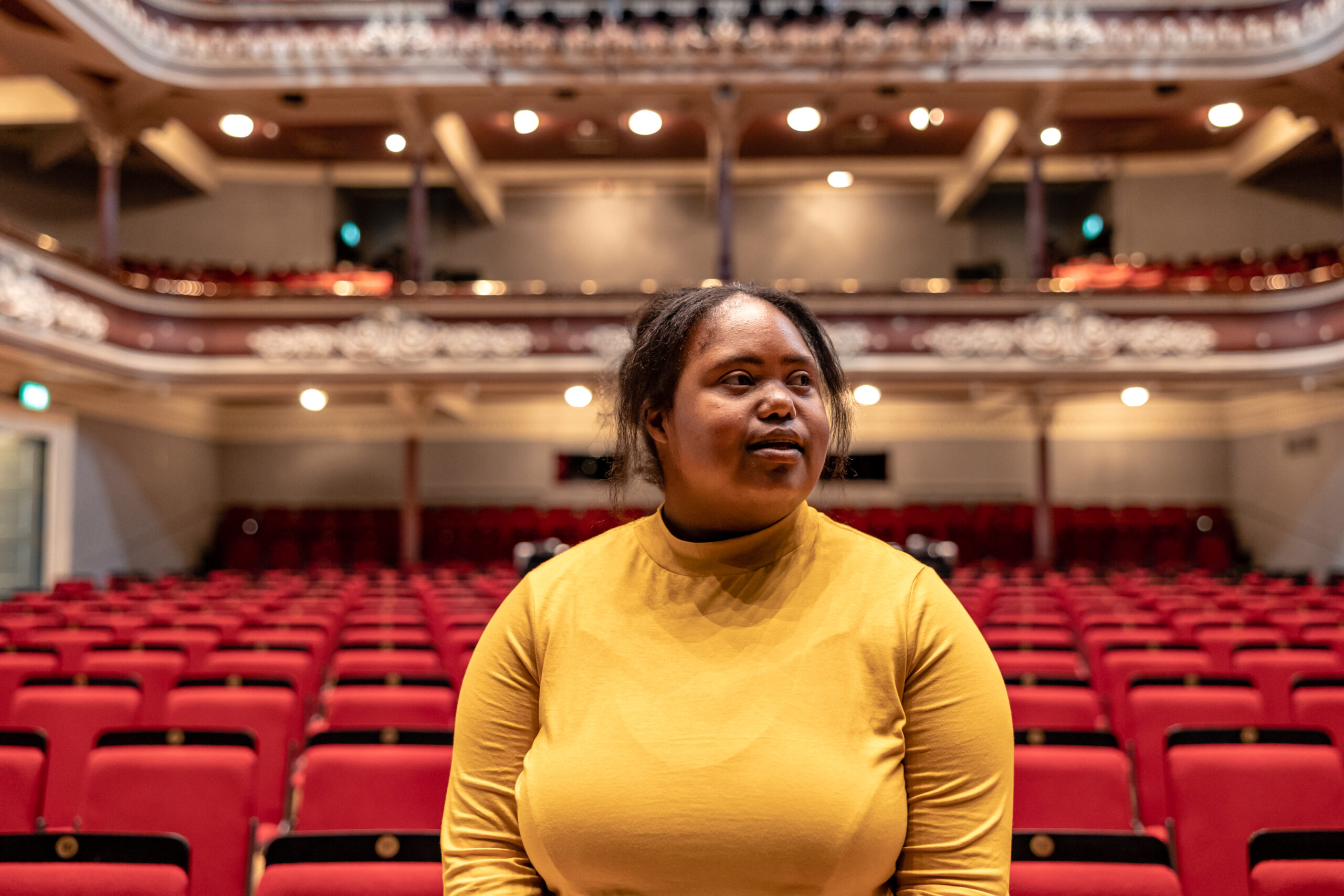 A black woman with a learning disability admires a grand theatre.